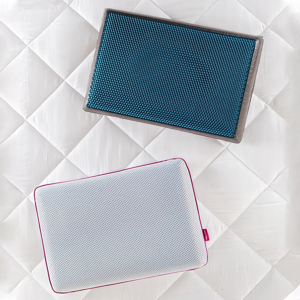 Dois travesseiros IWS Bubble Gel® com fundo branco, um travesseiro contendo sua capa levinha 100% poliéster com furinhos pequenos que permitem a passagem de ar mantendo o fresco do travesseiro durante toda a noite