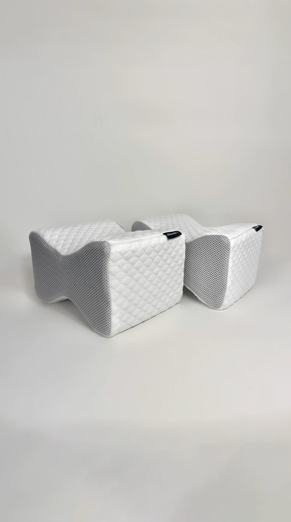 Dois travesseiros de joelho IWS Coluna Relax demonstrando os detalhes e sua textura acolchoada e acabamento com zíper para facilitar a remoção e a lavagem.