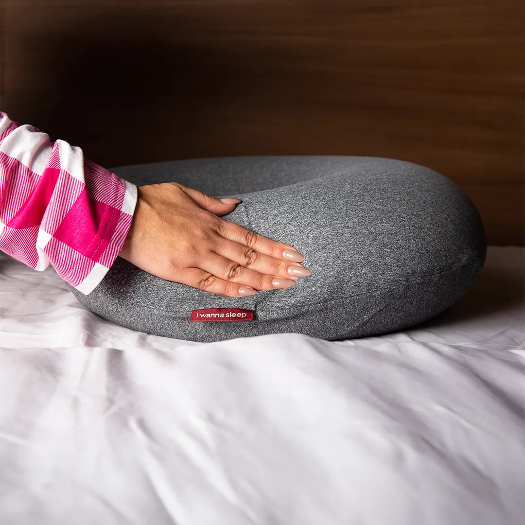 Almofada de amamentação confortável sendo pressionada por um mão feminina destacando sua maciez. Feita de memory foam, a almofada é macia e agradável ao toque, garantindo uma experiência acolhedora. Sua capa refrescante mantém a temperatura ideal, oferecendo uma superfície agradável para o bebê descansar enquanto se alimenta.