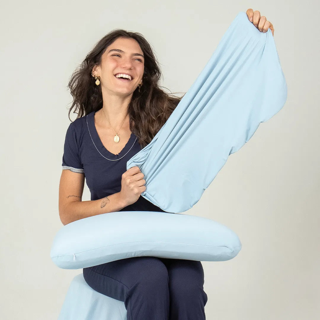 Mulher morena de pijama azul marinho da i wanna sleep mostrando a capa do travesseiro em Látex Blue Látex IWS, destacando sua leveza, flexibilidade e frescor. Nossa capa proporciona sensação de frescor instantâneo, garantindo um excelente conforto térmico e ideal para pessoas que sofrem com o calor.
