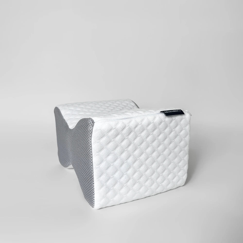 travesseiro de joelho coluna relax IWS sendo mostrado de forma lateral, pegando os detalhes de sua capa com textura acolchoada e acabamento com zíper para facilitar a remoção e a lavagem. Ideal para quem busca mais conforto e suporte durante o sono.