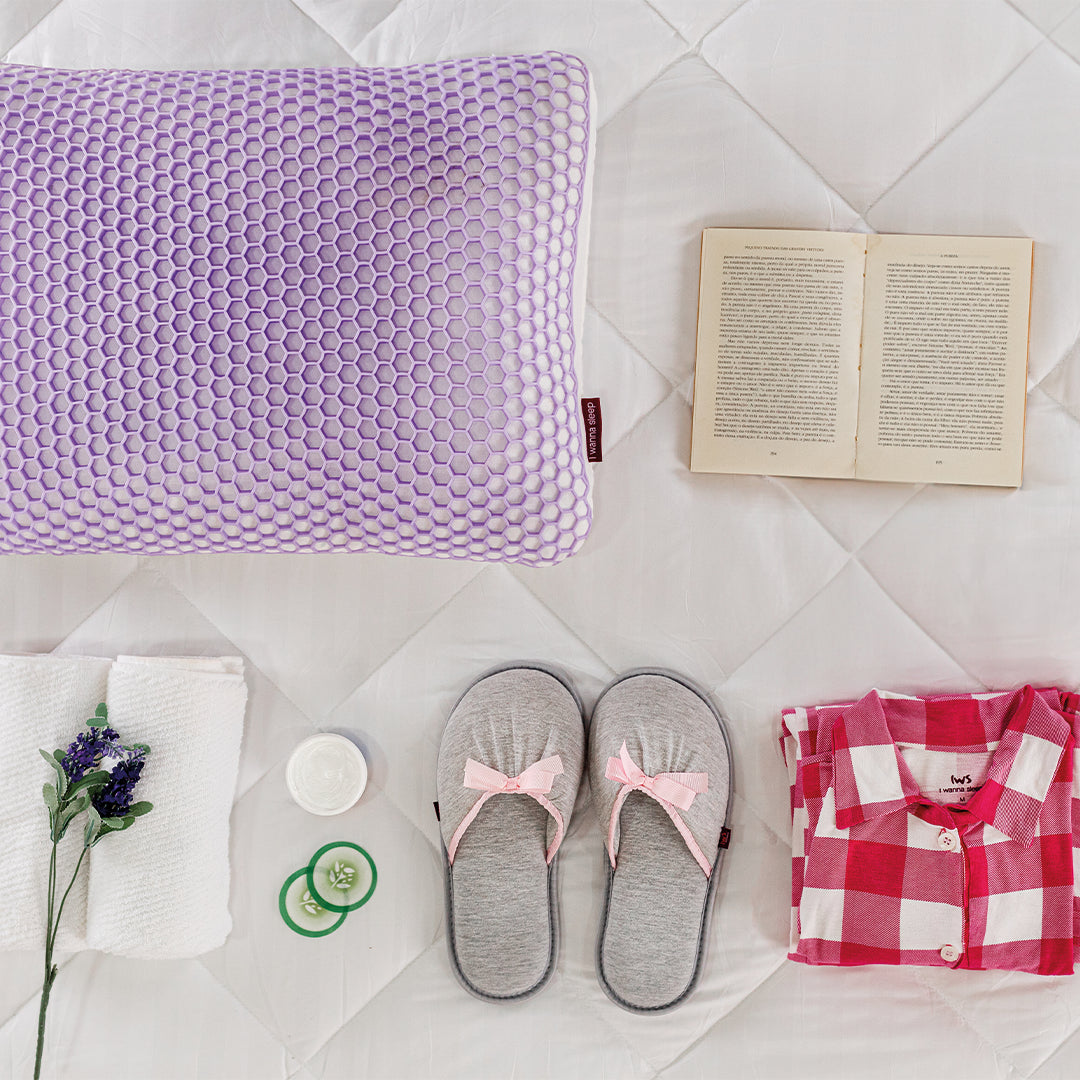 Kit de skin para quem gosta de se cuidar e ter dias relaxantes e noites de sono tranquilas, na imagem contém um livro aberto, um par de pantufas, um pijama rosa listrado, duas rodelas de pepino, uma toalha com uma flor de lavanda por cima e o travesseiro preferido de quem ama cuidar da pele, o travesseiro skin previne rugas do sono , possui maior higiene e conforto