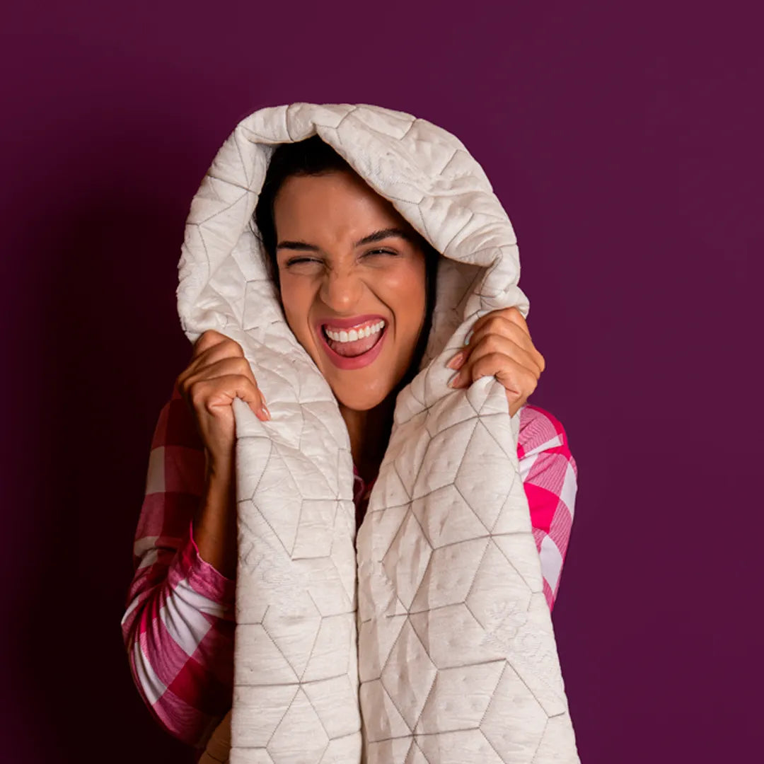 Mulher envolvida na capa para travesseiro Snow Body da I Wanna Sleep, expressando sensação de aconchego e frescor proporcionados pelo material respirável.