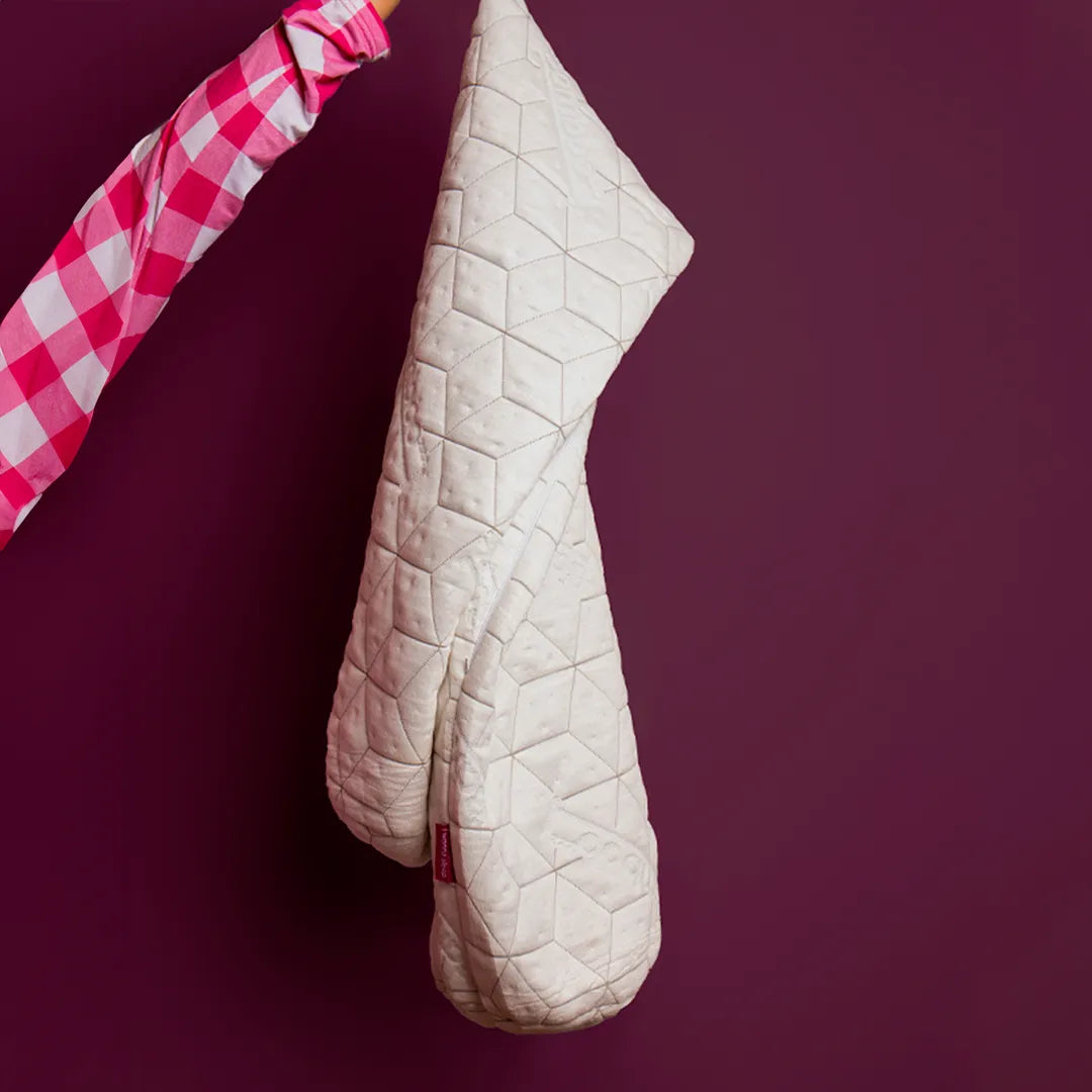 Mão feminina com o  pijama xadrez rosa e branco segurando a capa do travesseiro de corpo Snow Body da I wanna sleep com um fundo roxo