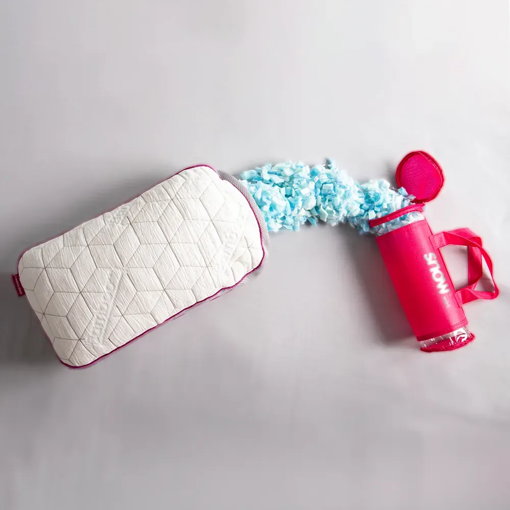 Travesseiro de viagem Snow Mini da I Wanna Sleep ao lado de sua embalagem compacta rosa, com espuma viscoelástica ajustável saindo do interior, destacando sua regulagem de altura e praticidade para transporte.